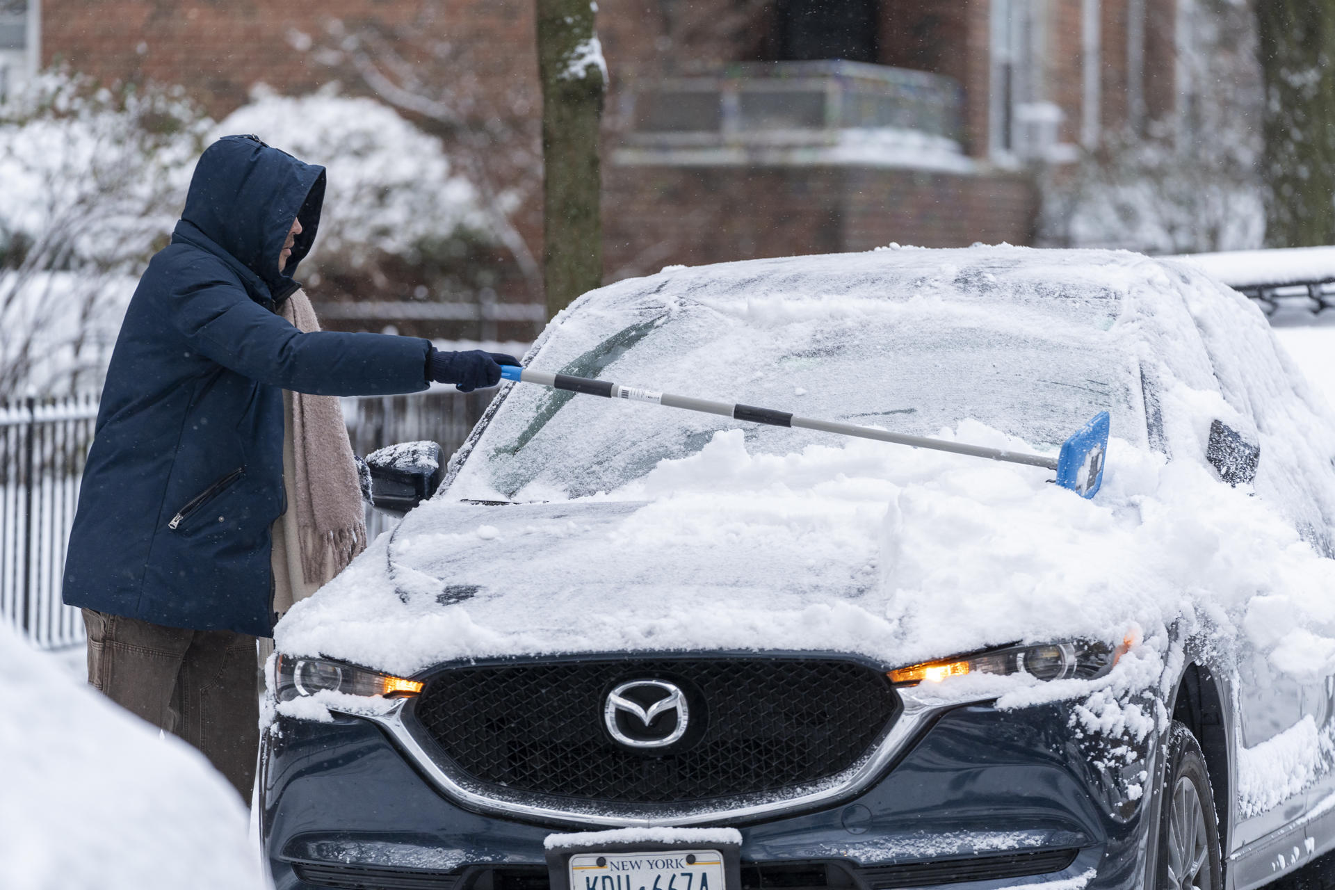 Una persona limpia su carro cubierto de nieve este sábado en Queens, New York (EE.UU.). EFE/Ángel Colmenares