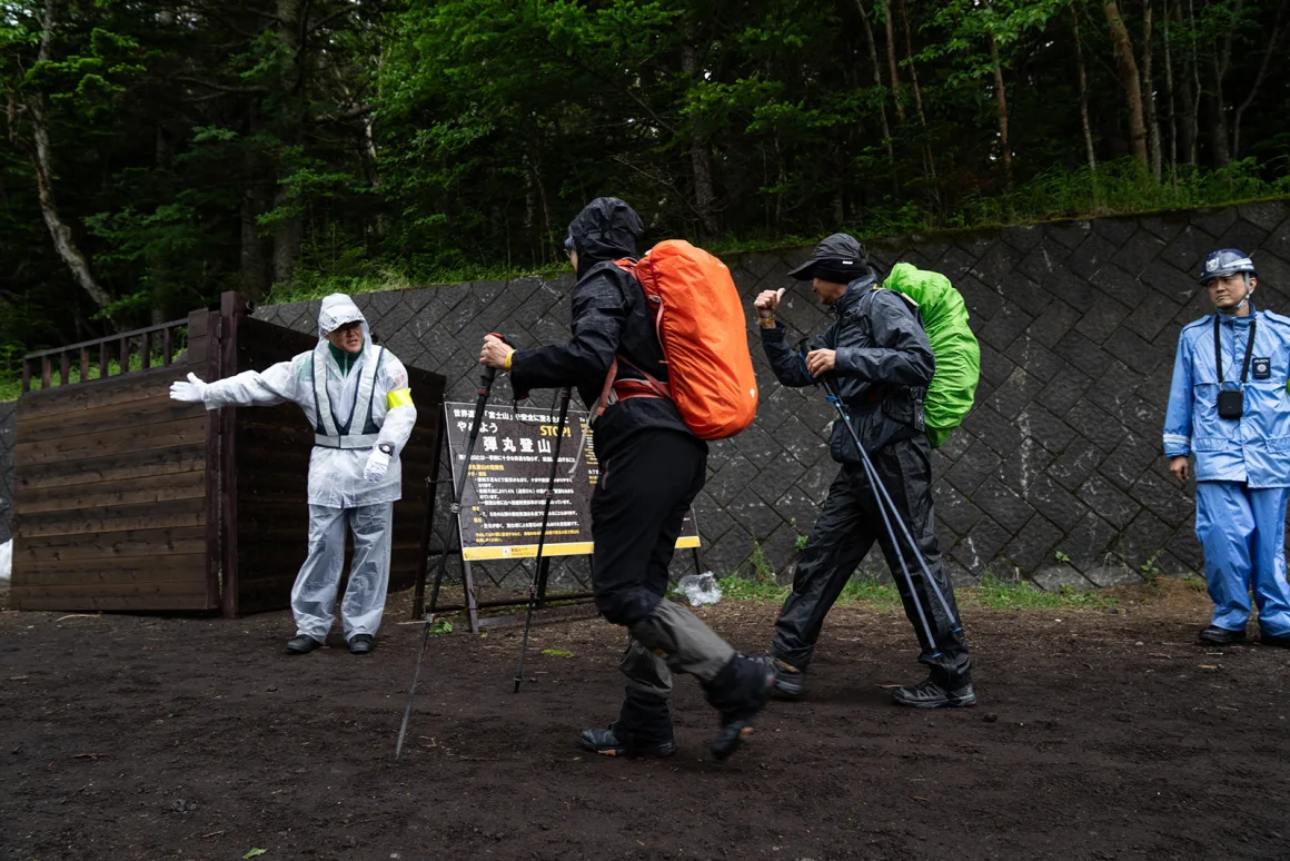 Un miembro del personal controla a los excursionistas en el sendero Yoshida del monte Fuji sus pulseras, la prueba del pago de la tarifa de la caminata. Zhang Xiaoyu/Xinhua/Getty Images