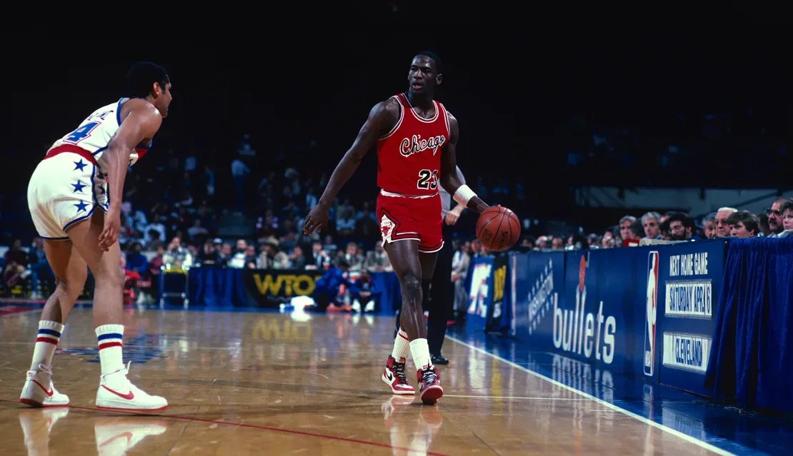 Michael Jordan dribla el balón en la cancha durante un partido de baloncesto de la NBA alrededor de 1985 en el Capital Centre en Landover, Maryland. Enfoque en el deporte/Getty Images