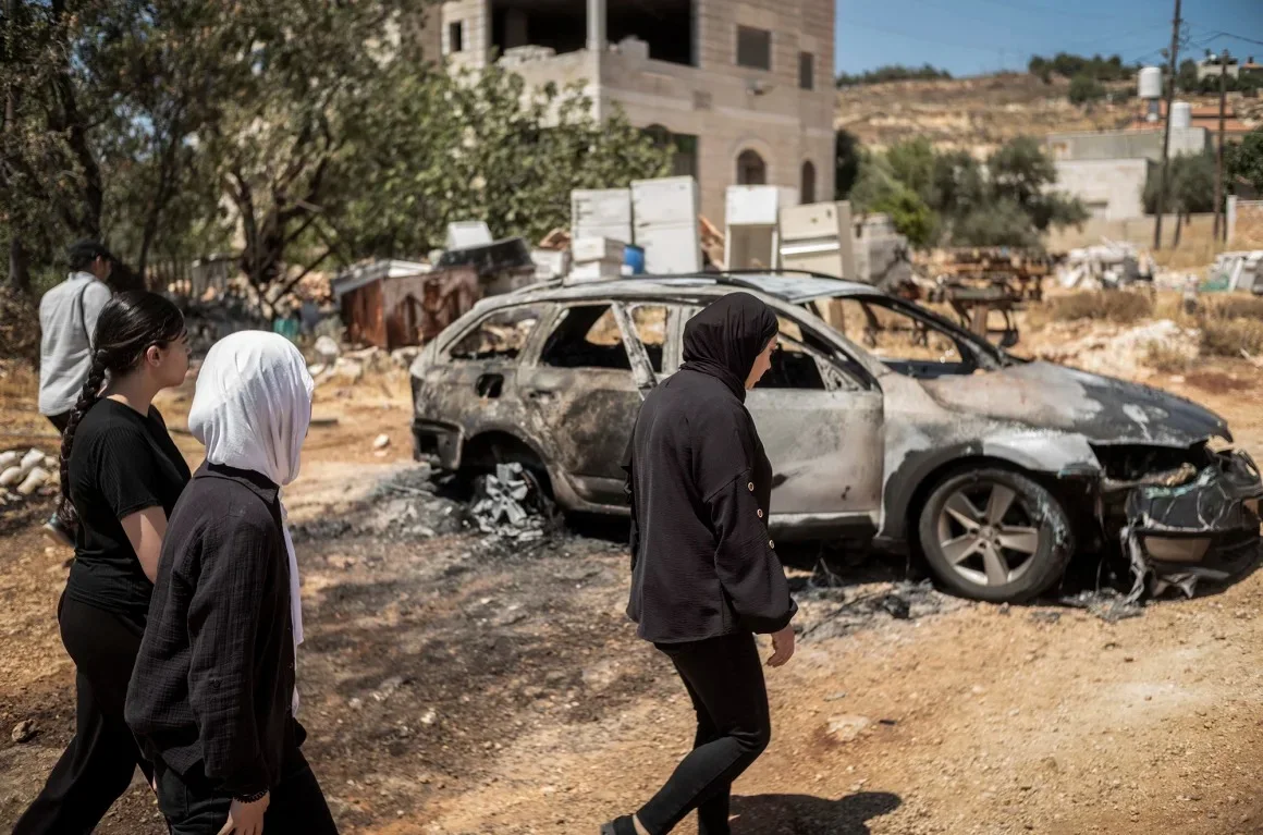 Mujeres palestinas caminan junto a un vehículo carbonizado, mientras observan la destrucción causada por los colonos israelíes en la aldea de Kafr Malik en Cisjordania, este jueves. Ilia Yefimovich/picture alliance/Getty Images