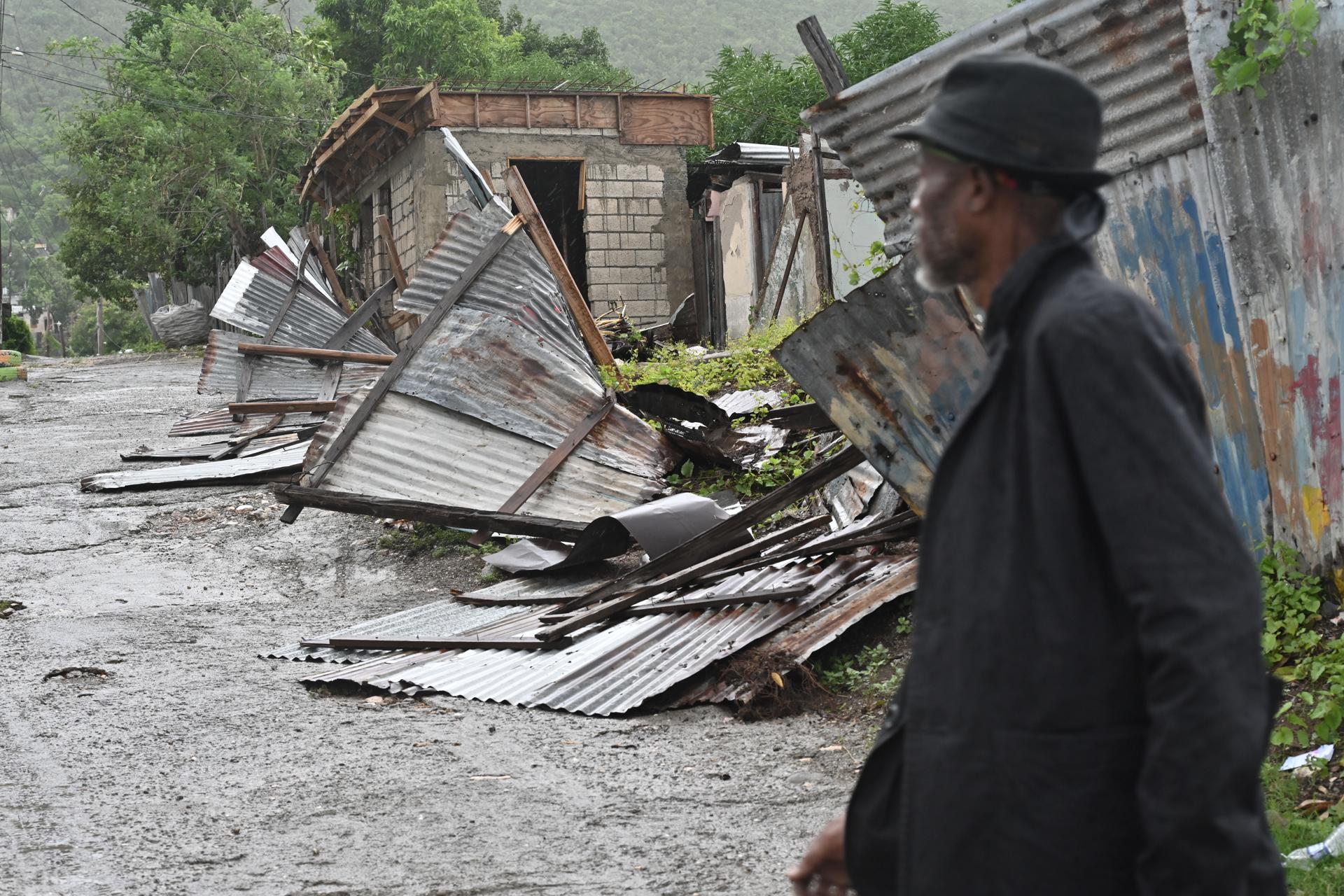 Una persona camina frente a una casa afectada por el paso del huracán Melissa este martes, en Kingston (Jamaica). EFE/Rudolph Brown