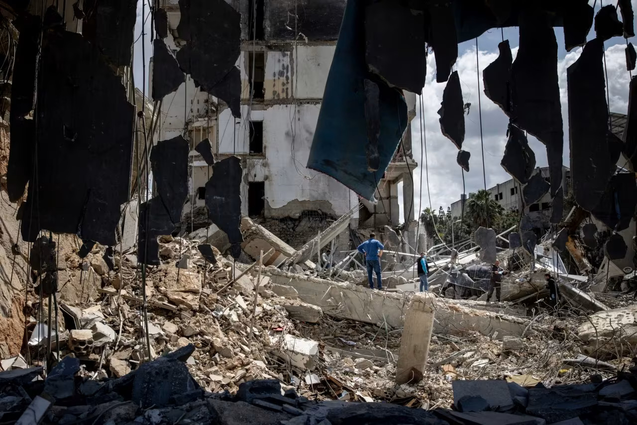 Trozos de hormigón roto cuelgan del primer piso mientras la gente trabaja para retirar los escombros de la mezquita Al-Zahraa, que fue destruida en un ataque aéreo israelí días antes en Sidón, Líbano, el 10 de abril.