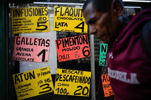 Un hombre pasa junto a un supermercado que exhibe carteles con los precios de los alimentos en dólares estadounidenses en Caracas, el 22 de abril. Federico Parra/AFP/Getty Images