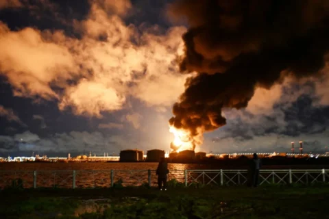 Varias personas observan la terminal petrolera en llamas tras un ataque aéreo en San Petersburgo, Rusia, el 18 de octubre de 2026. AFP/Getty Images