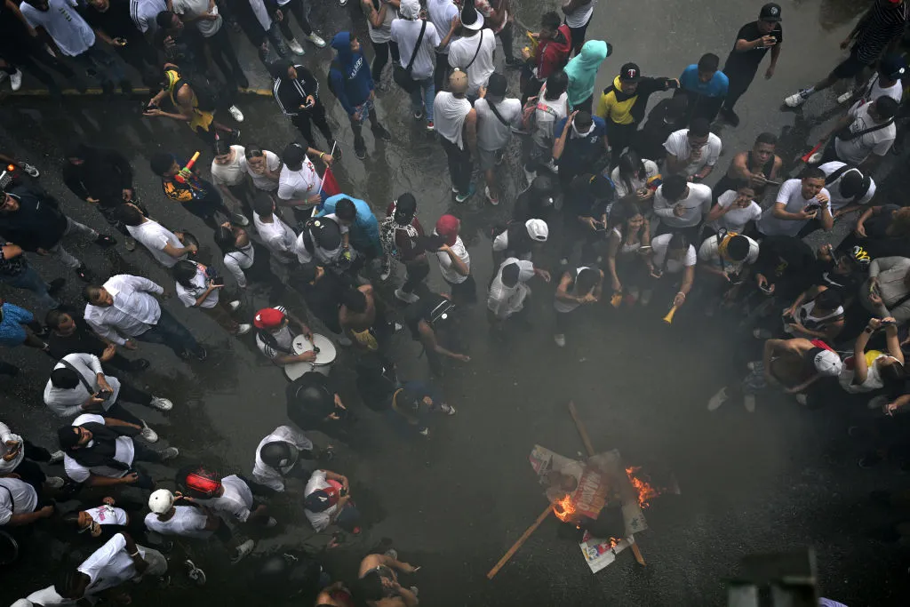 Opositores al gobierno del presidente venezolano Nicolás Maduro queman carteles de la campaña de Maduro durante una protesta en el barrio Petare en Caracas el 29 de julio de 2024. Crédito: RAUL ARBOLEDA/AFP vía Getty Images