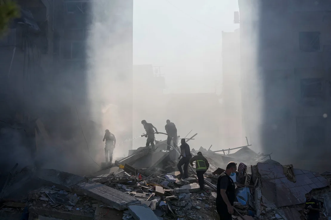 Los trabajadores de protección civil extinguen un incendio mientras se eleva humo desde el lugar del ataque aéreo. Hassan Ammar/AP