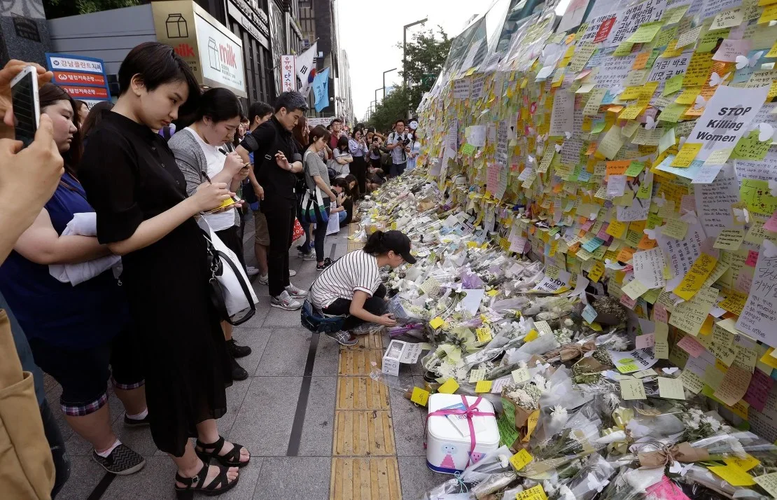 Una mujer coloca una flor en memoria de una mujer surcoreana que fue apuñalada hasta la muerte en la salida de la estación de metro Gangham en Seúl el 21 de mayo de 2016. Ahn Young-joon/AP