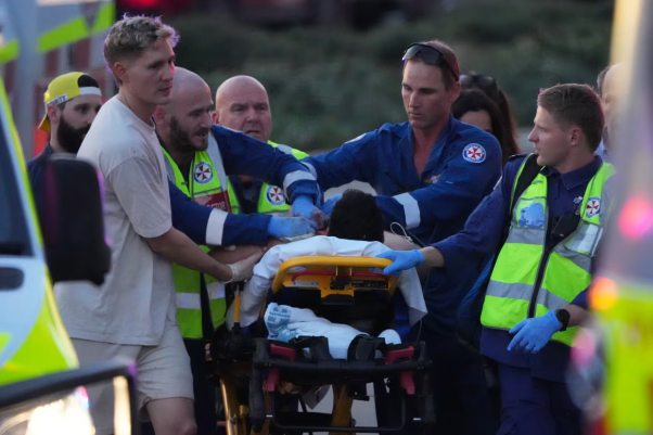 Los trabajadores de emergencia transportan a una persona en una camilla después de un tiroteo reportado en Bondi Beach, en Sydney el domingo. Mark Baker/AP